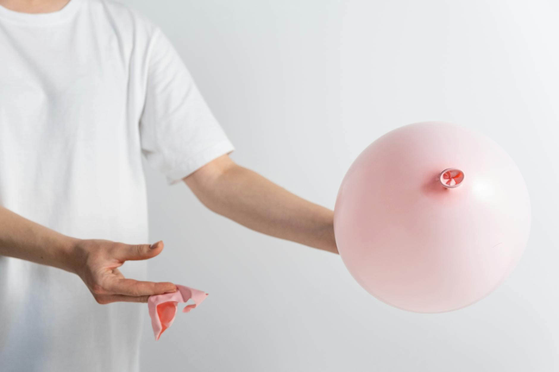 person in white shirt holding a pink balloon